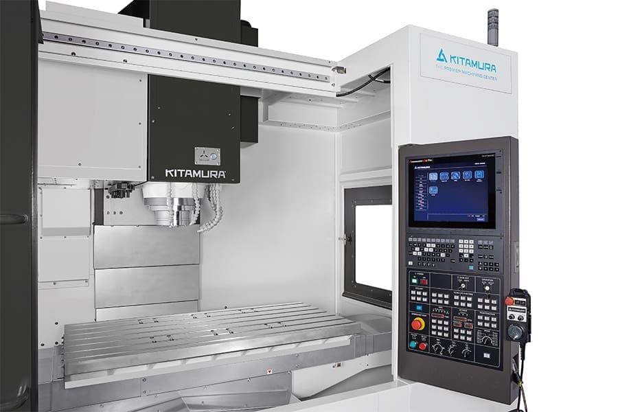 Close-up of a Kitamura vertical machining center with an advanced CNC control panel and a large, empty worktable ready for operation.