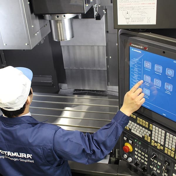 Industrial worker operating cnc machine control screen.