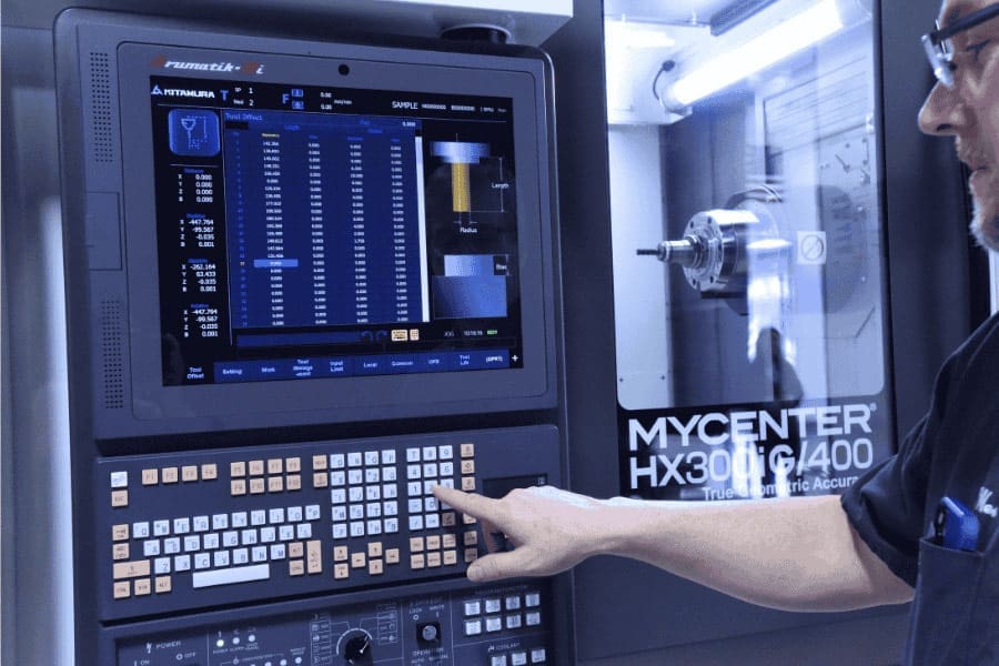 Person operating a CNC machine using the Arumatik-Mi control panel, displaying a tool data interface on a large screen with the machine labeled 