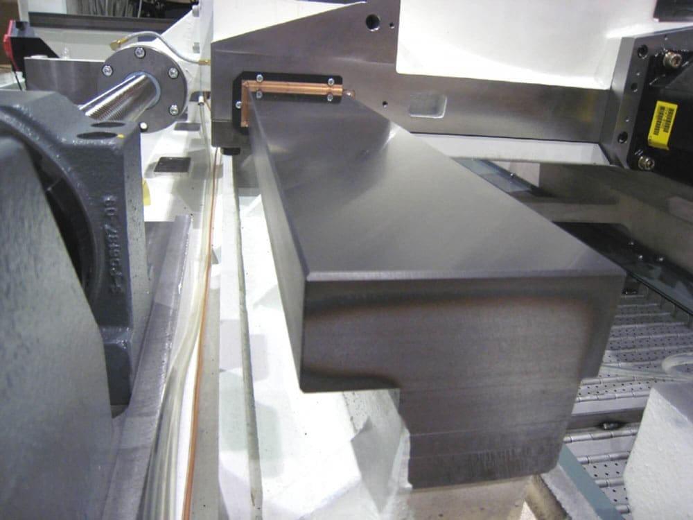 A close-up view of a precision-machined metal surface on industrial equipment, showcasing a smooth, reflective guideway.